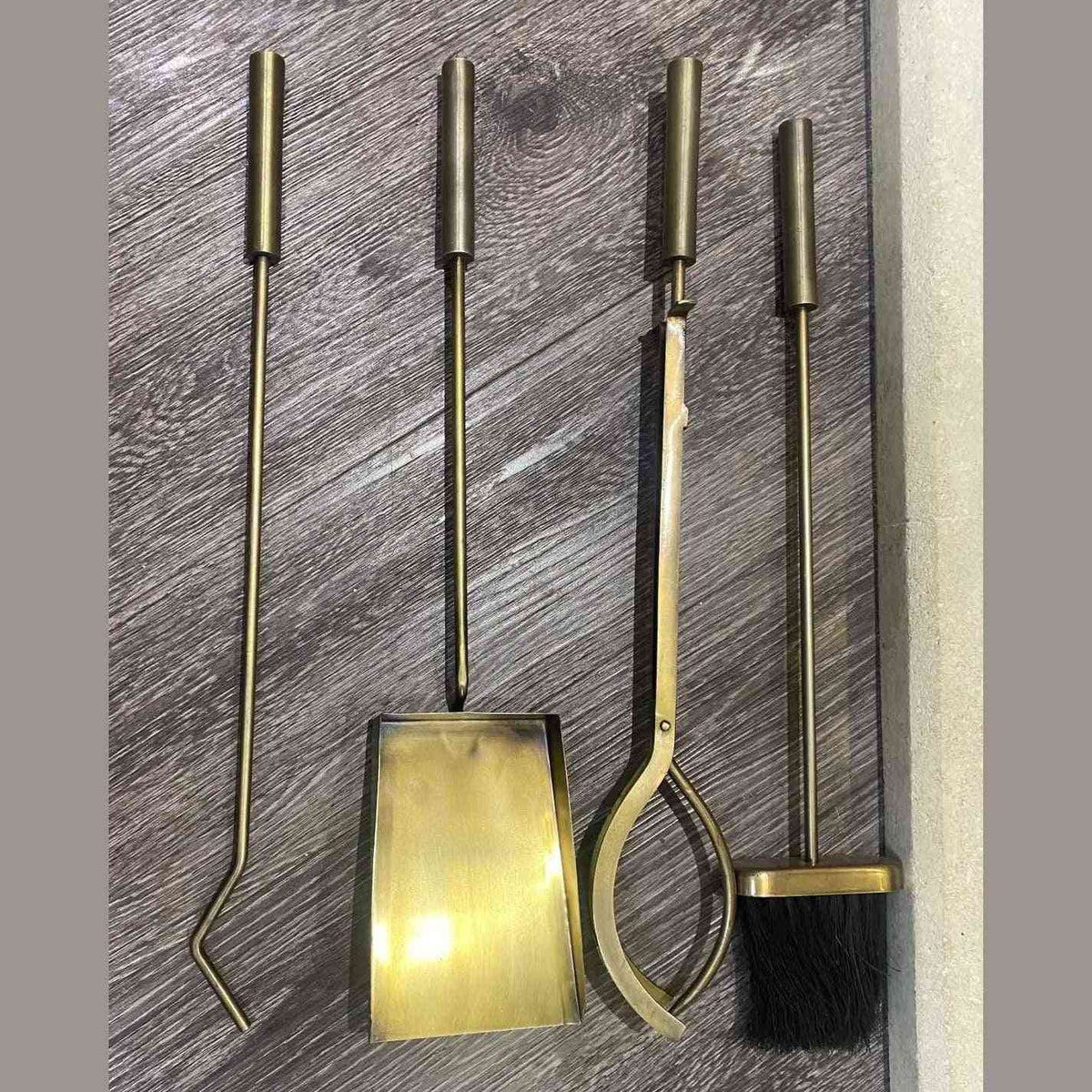 Antique brass poker, log grabber, brush and dustpan laid out flat