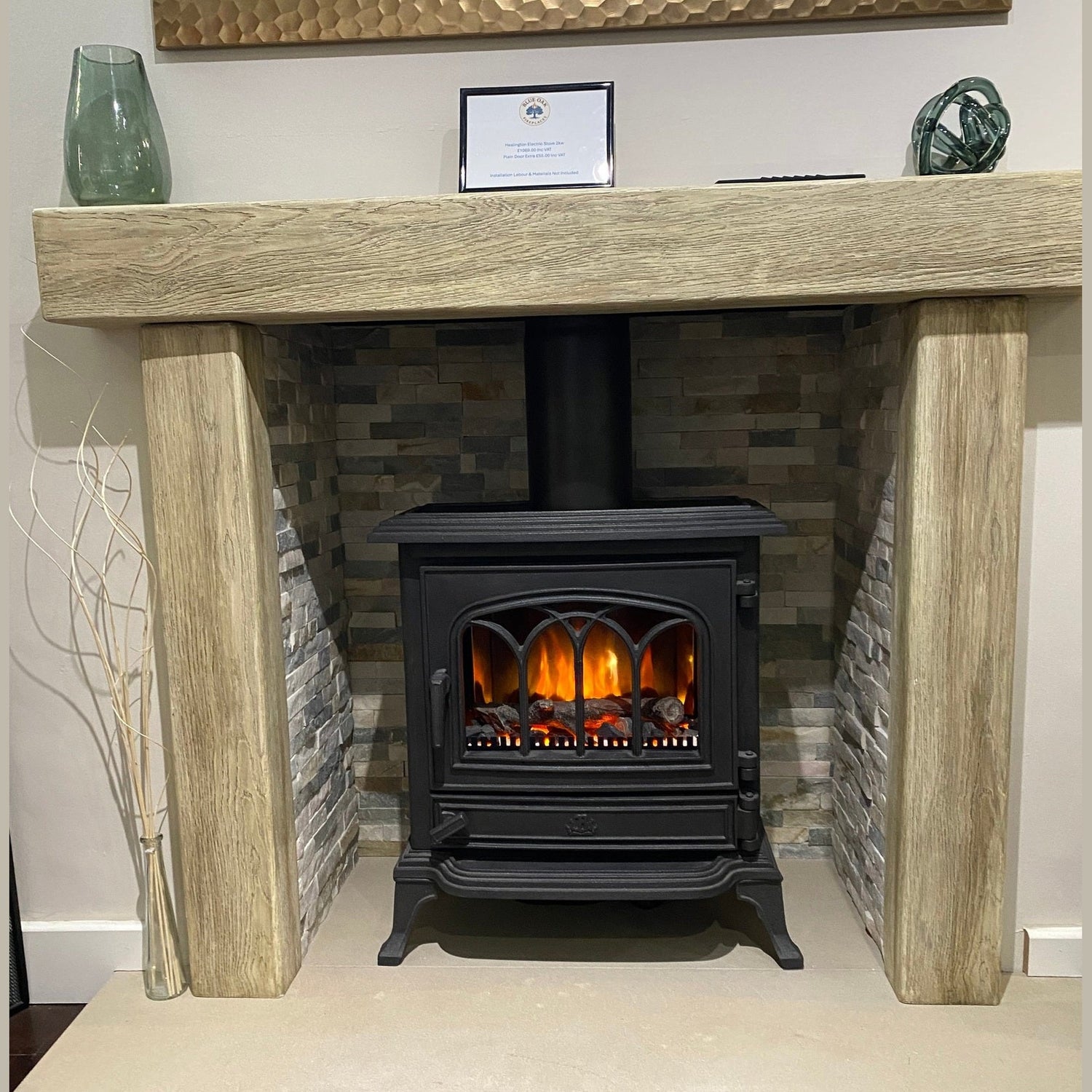 Traditional black electric stove log burner with realistic glowing flame effect inside a rustic oak beam fireplace surround.