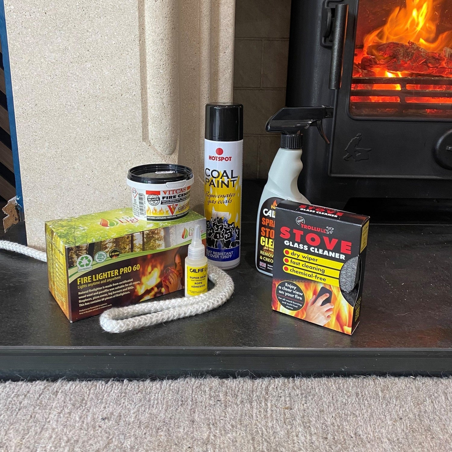 Wood burner maintenance kit with stove rope, glass cleaner, fire cement, coal paint, and firelighters.