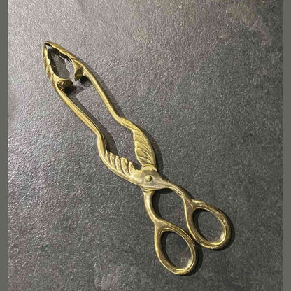 Top-down view of brass coal tongs showing oval loops and pivot