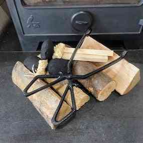 Heavy-duty cast iron log tongs holding charcoal briquettes near stove