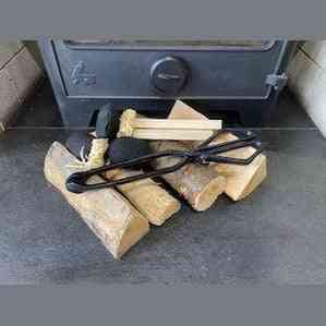 Black cast iron coal tongs gripping kindling and briquettes for fireside use