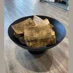 Top view of black steel garden fire bowl with cut firewood