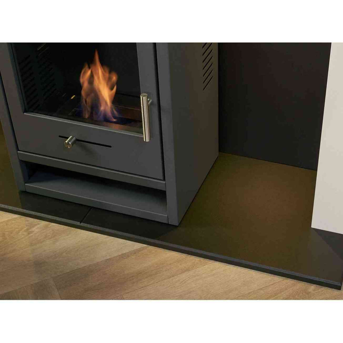 Charcoal grey OKO S1 bio ethanol stove installed in media wall with active flame and hearth