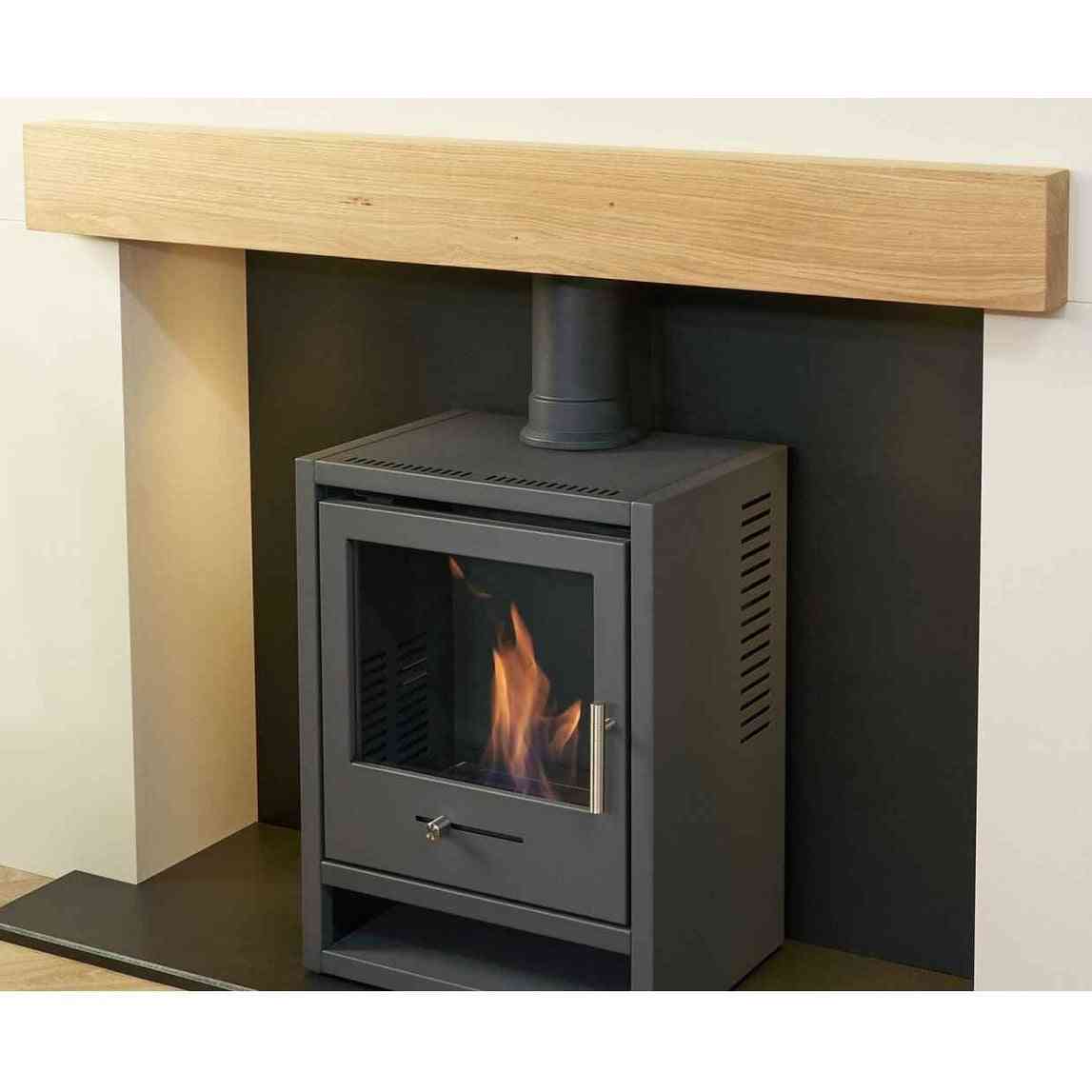 Side view of charcoal grey OKO S1 stove in media wall with ventilation slits and oak beam detail