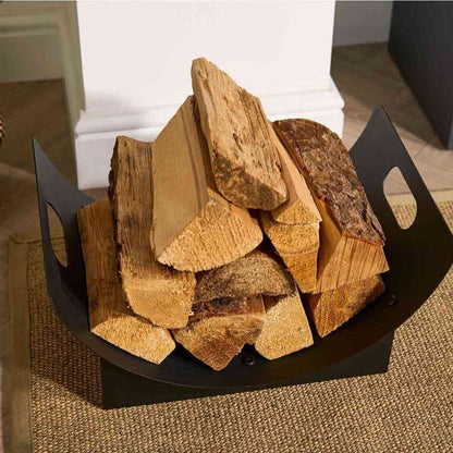 Black steel freestanding firewood log holder with curved basin and cutout handles filled with stacked logs