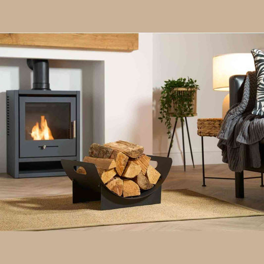 Black metal log rack holding firewood beside a lit wood-burning stove in a modern living room