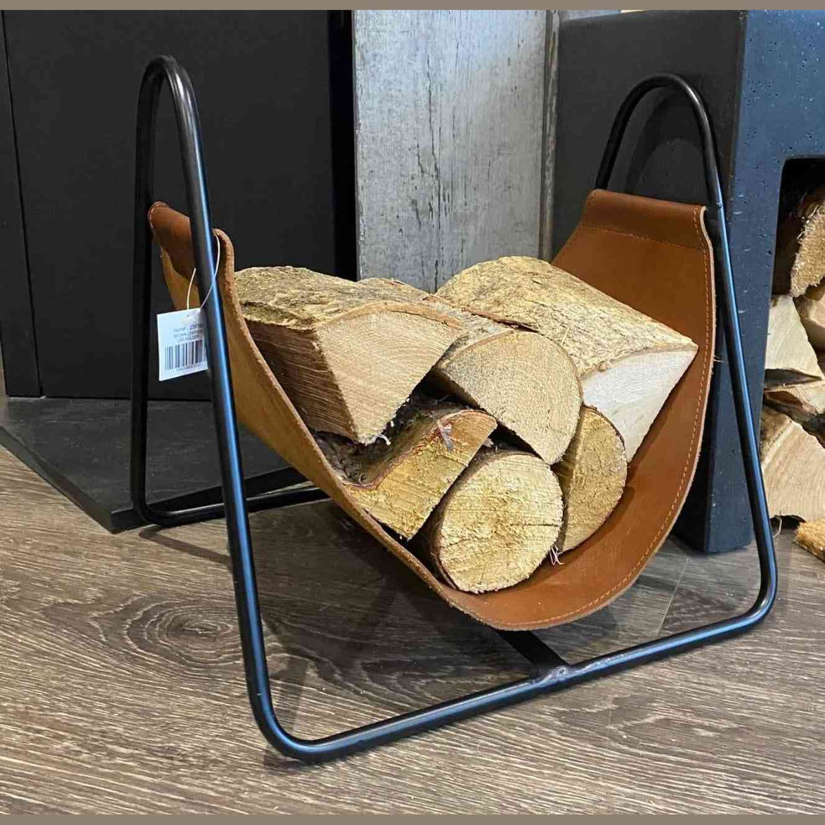 Apache brown leather log holder basket with black metal frame holding firewood beside fireplace
