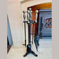 Traditional black fireside companion set in stand with silver ball handles beside lit wood stove