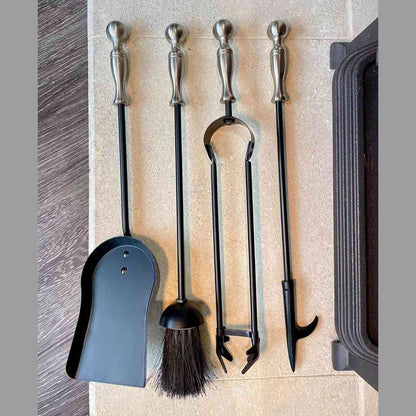 Black and pewter ball top fireplace tool set with dustpan, brush, tongs, and poker on stone hearth