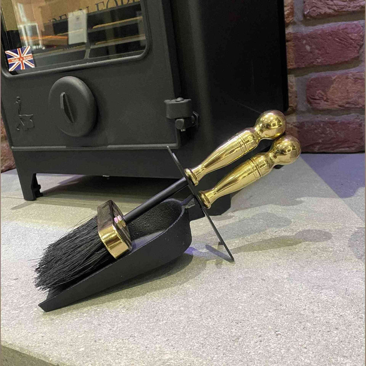 Calfire black cast iron fireplace shovel and brush set with brass handles on stone hearth