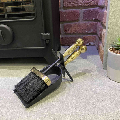 Calfire 2-piece fireplace maintenance kit with brass details beside wood-burning stove