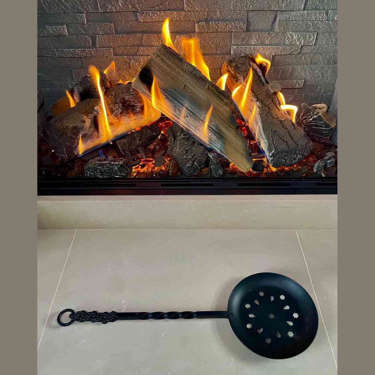 Calfire wrought iron chestnut roaster with long handle over fireplace flames