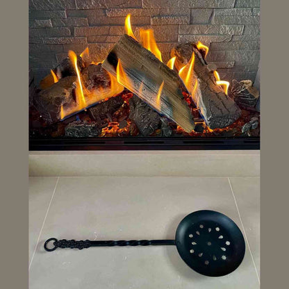 Calfire wrought iron chestnut roaster with long handle over fireplace flames