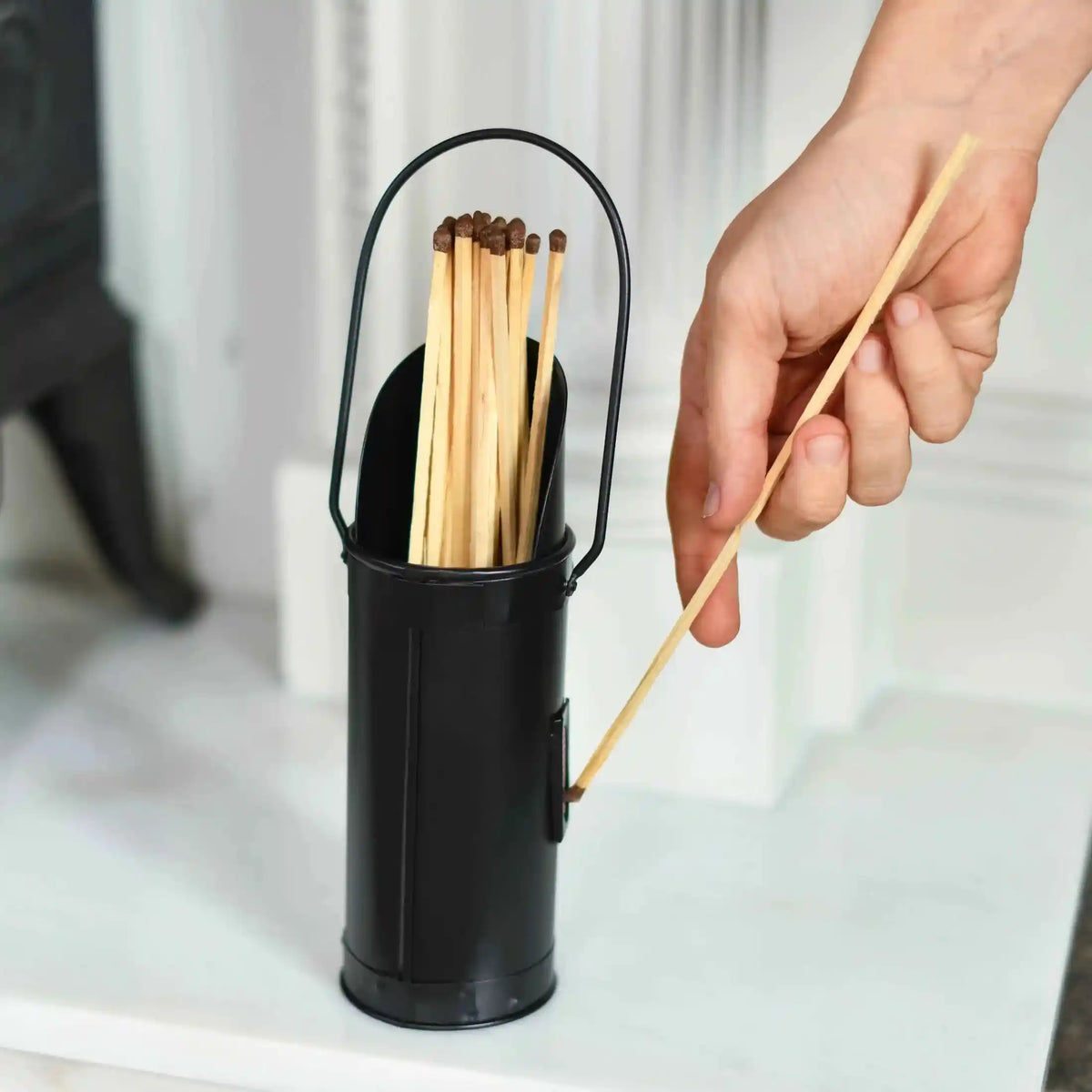 Hand pulling long wooden match from black Calfire fireplace match holder on mantel