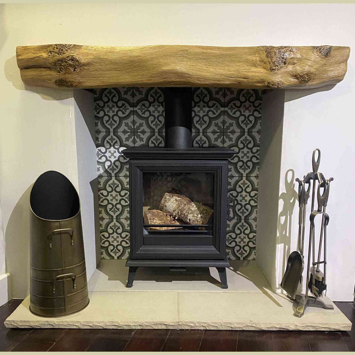 Antique pewter coal bucket beside black wood-burning stove in fireplace scene