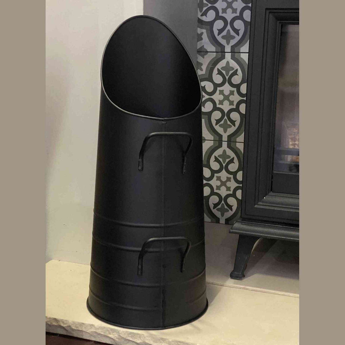Close-up of tapered black metal coal scuttle with riveted handles