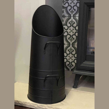 Close-up of tapered black metal coal scuttle with riveted handles