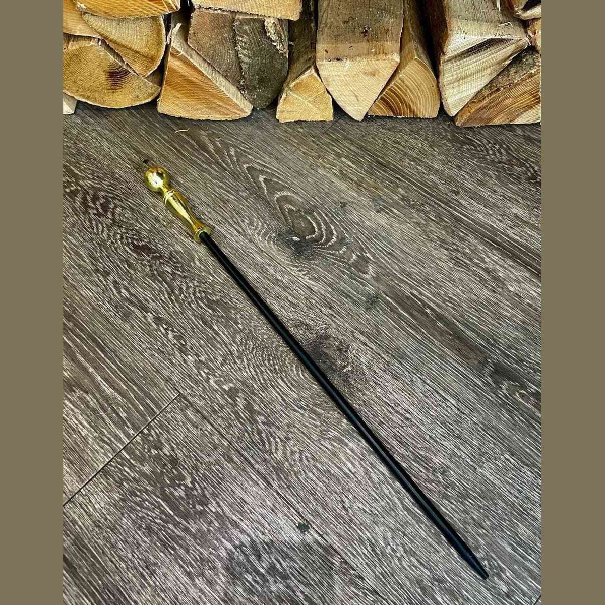 Calfire cast iron fire poker with gold brass spherical handle on wood floor