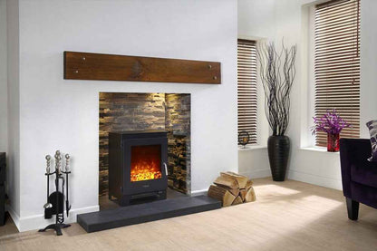 Elegant living room interior displaying a Celsi electric log burner stove tucked into a textured stone fireplace chamber with a dark wooden beam mantelpiece overhead.