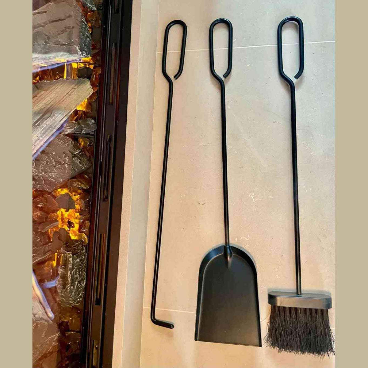 Side view of black wrought iron fireplace tools with U-shaped handles