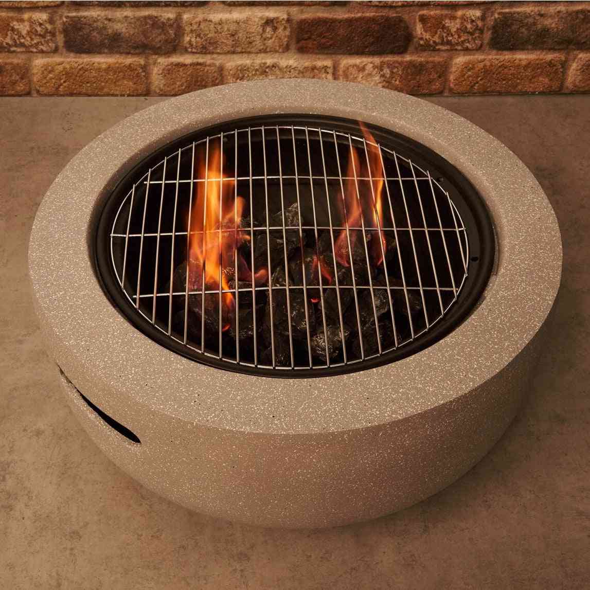 Concrete grey charcoal fire pit with metal grate against brick wall backdrop