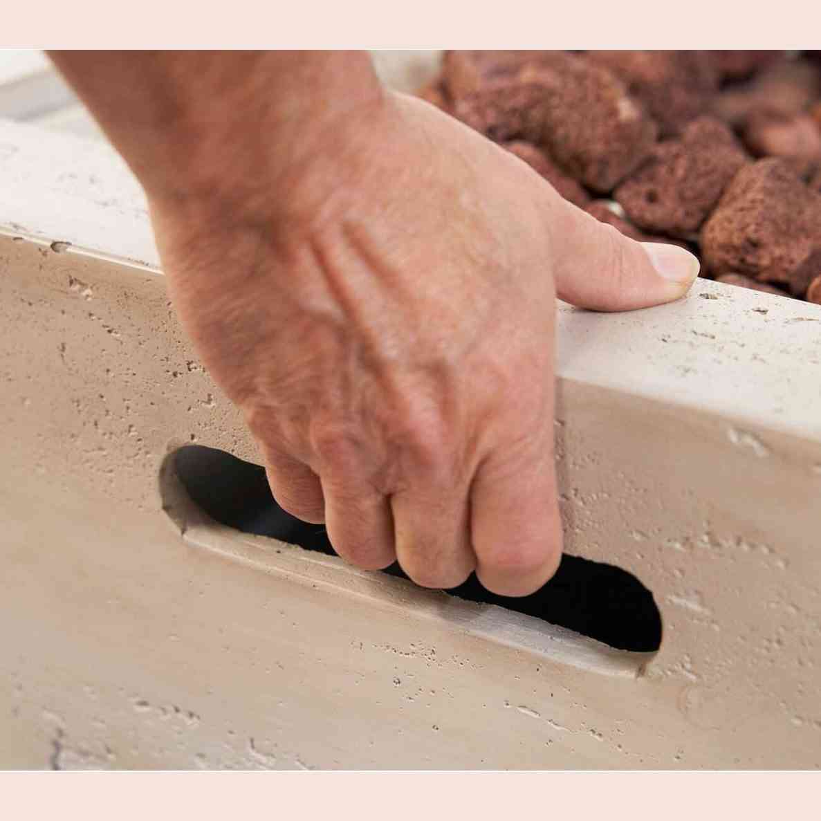 Close-up of ergonomic recessed handle on textured concrete fire pit side