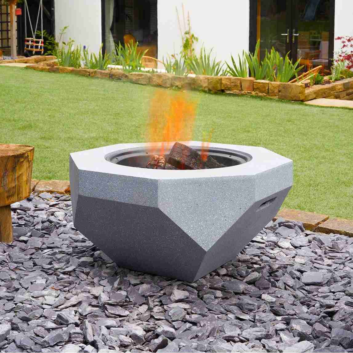 Concrete grey fire pit heating backyard beside modern house