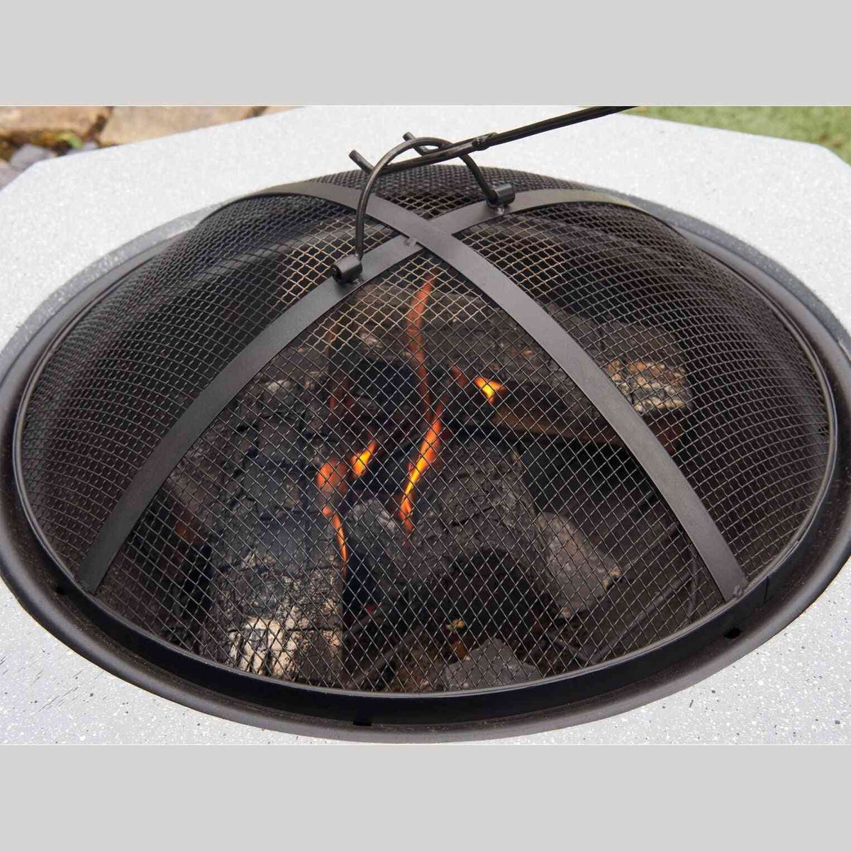Close-up of black mesh lid over glowing embers in concrete fire pit