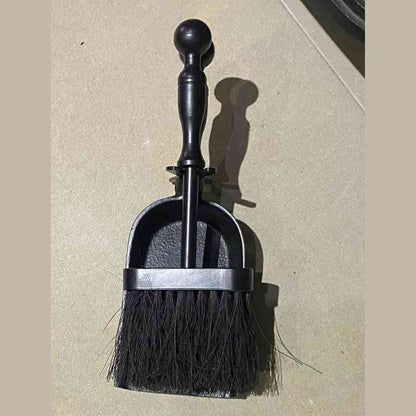 Close-up of black cast iron ash shovel with stiff bristle brush
