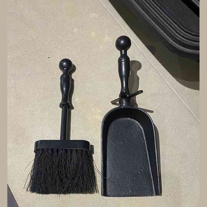 Black cast iron ash shovel and brush cleaning set on tiled floor