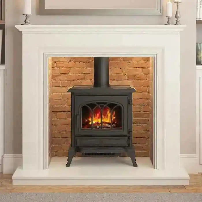 Matt black Heslington electric stove on splayed legs inside white marble fireplace mantel with red brick wall