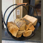 Ivyline black iron round log holder with leather handles holding firewood on stone hearth