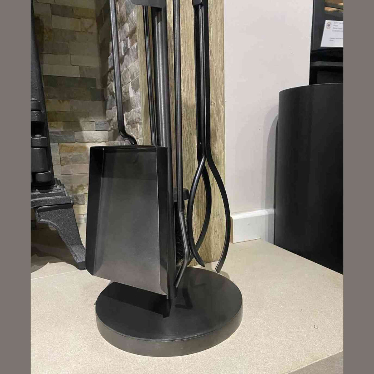 Side view of black metal fireplace companion set with shovel and tongs on stand