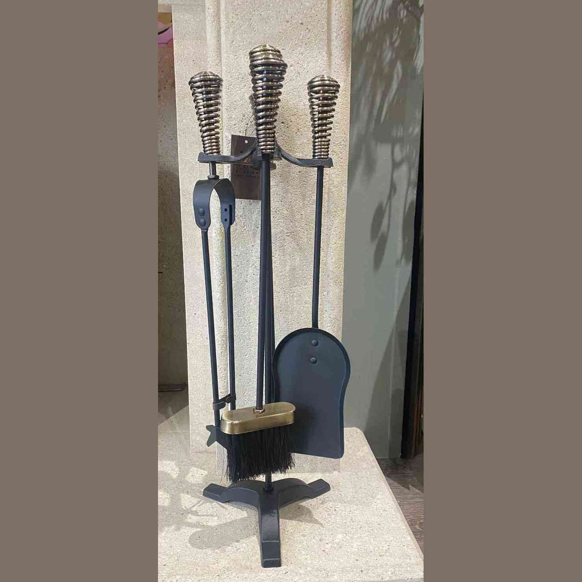 Centered shot of five-piece black fireplace tool set with antique silver accents on stone
