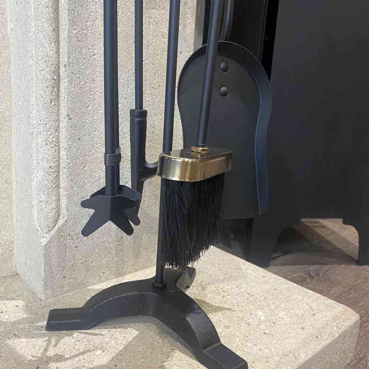 5-piece black iron fireplace tool set with antique brass handles and star poker on stone hearth