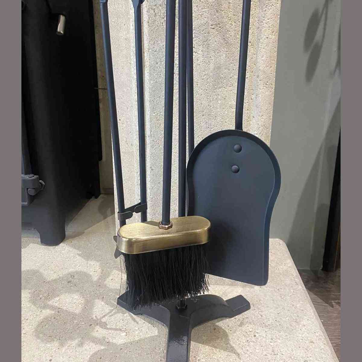 Side angle of black iron fireplace tools with brushed brass brush handle and riveted shovel