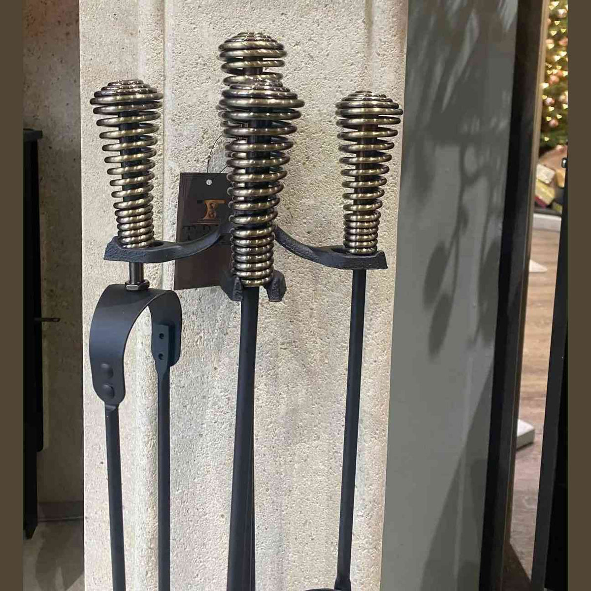 Close-up of coiled spring-style brass handles on black metal fireplace tool frame