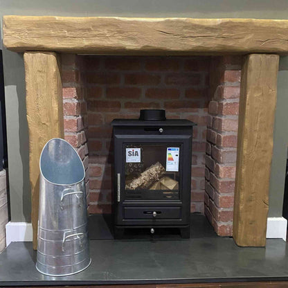 Zinc coal hod beside black wood-burning stove on slate hearth