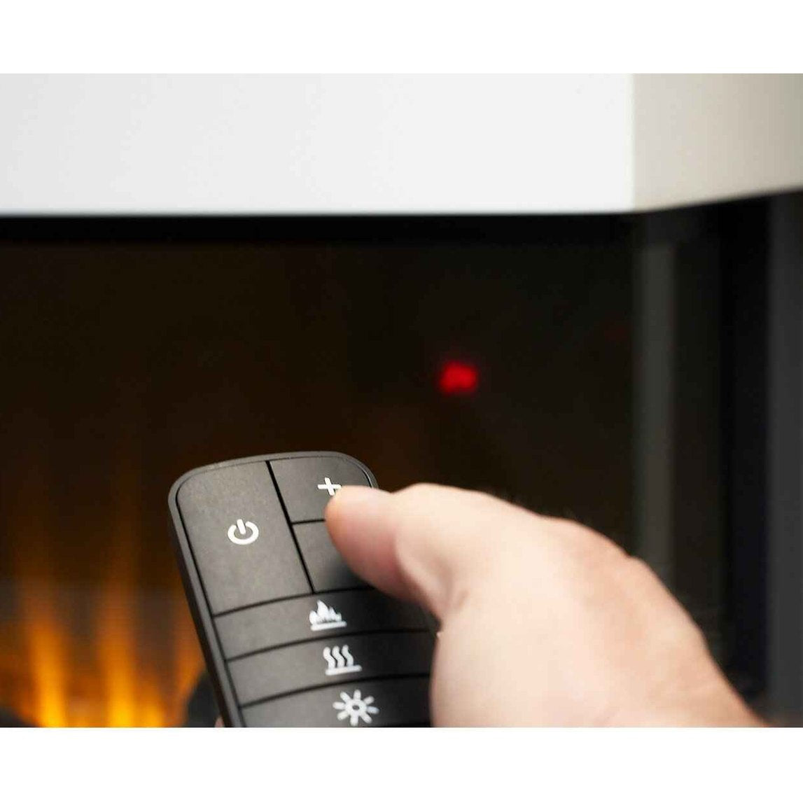 Hand holding a smart remote control adjusting the flame settings of a modern media wall fireplace