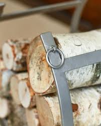 A close-up view of the top of the pewter log holder, featuring ring detailing on the strap, stacked neatly with birch wood logs
