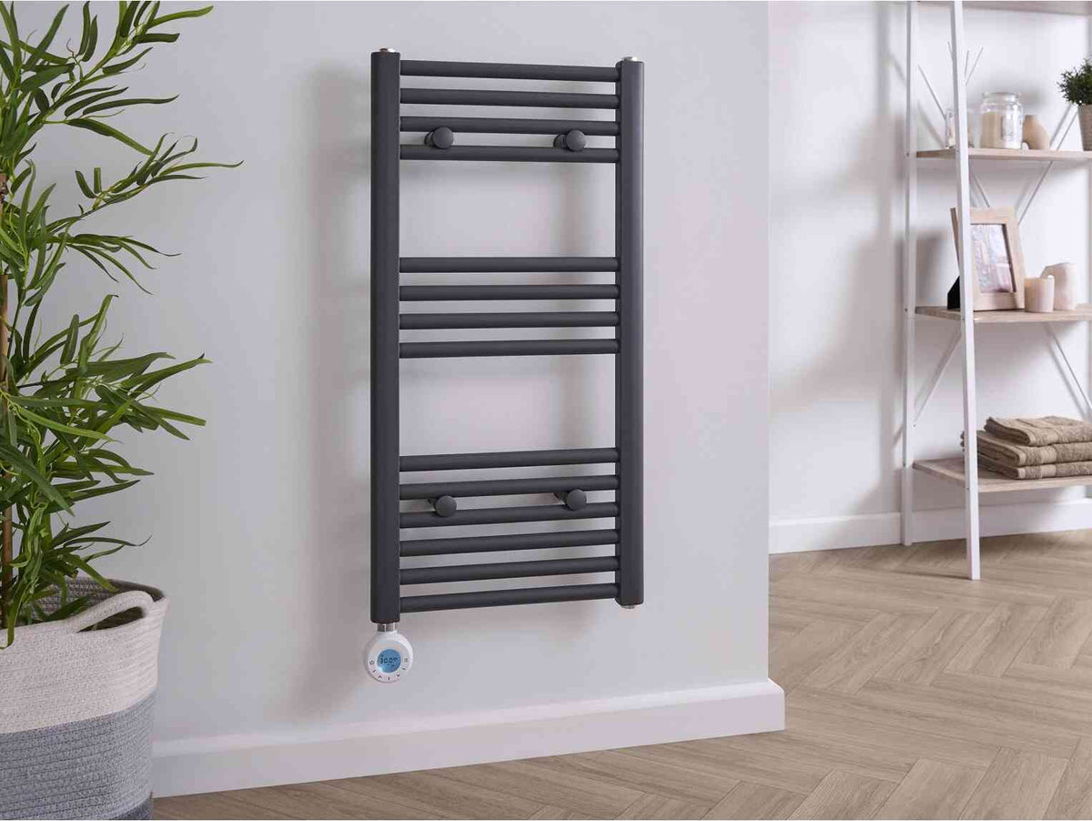 Grey electric towel radiator with horizontal bars and digital thermostat control mounted on a white wall in a modern bathroom