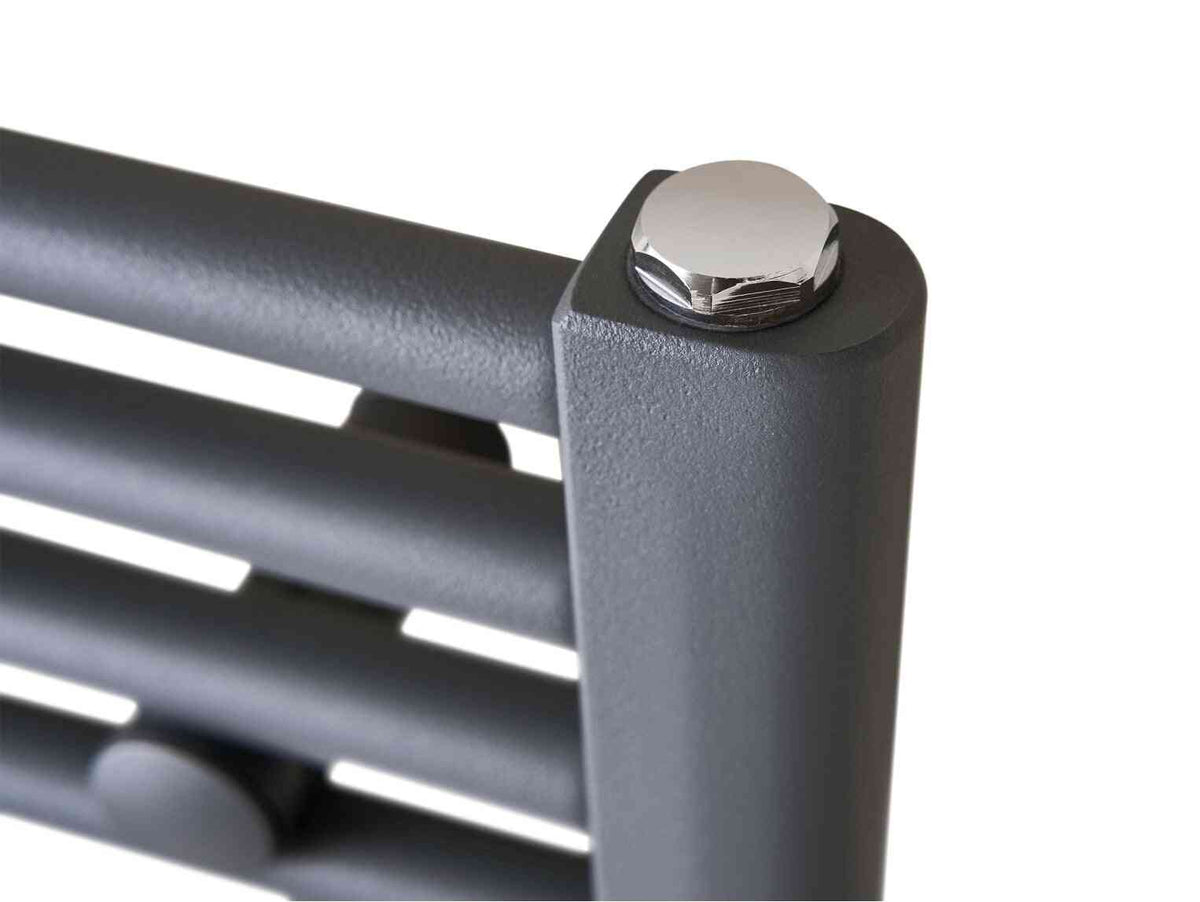 Close-up of a modern black metal slatted radiator with a shiny chrome bolt on the top corner, designed for home heating and bathroom use