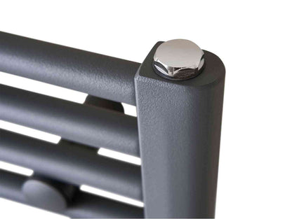Close-up of a modern black metal slatted radiator with a shiny chrome bolt on the top corner, designed for home heating and bathroom use