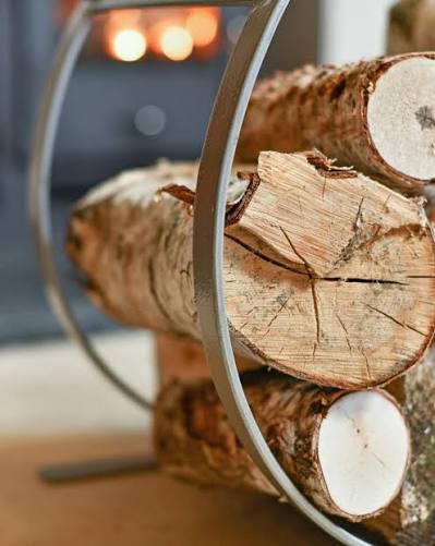 A close-up view of the top of the pewter log holder, featuring ring detailing on the strap, stacked neatly with birch wood logs