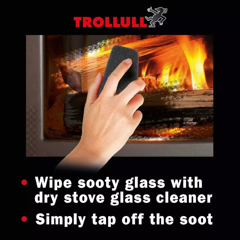 Close-up of a hand using the Trollull dry wiper pad to clean soot off a wood-burning stove glass door.